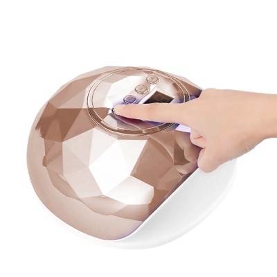 Dispositivo elétrico facetado bronze e branco com painel de botões e mão a tocar