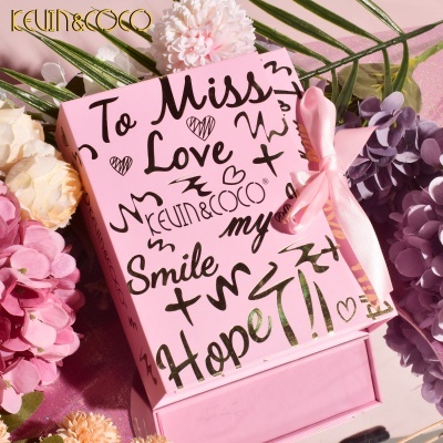 Caixa de presente rosa decorada com texto e laço, rodeada por flores variadas