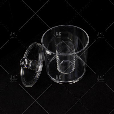 Recipiente de vidro transparente com tampa e compartimento interno sobre fundo preto