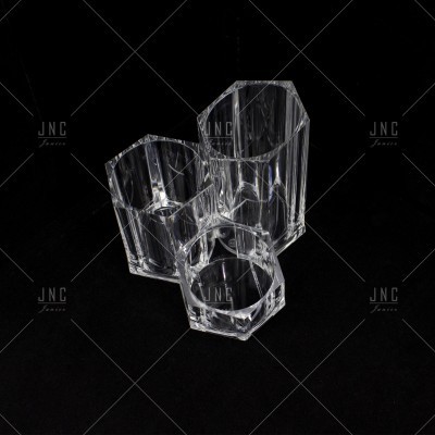 Três copos de vidro transparente com texturas facetadas sobre fundo preto