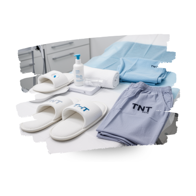 Conjunto de chinelos, calças, toalhas e álcool gel numa cama médica