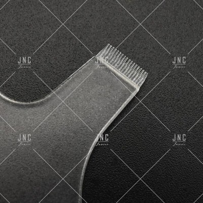 Utensílio de plástico translúcido com dentes pequenos sobre fundo preto texturizado