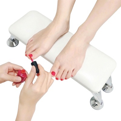 Banco almofadado branco com pernas metálicas cromadas e pés com verniz vermelho sendo aplicado