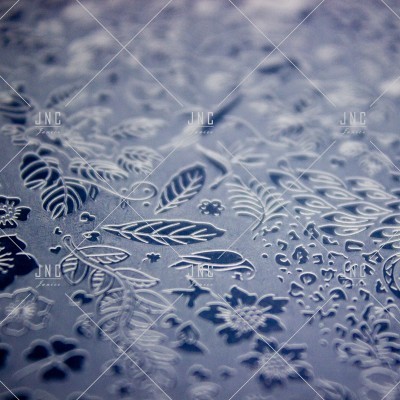 Superfície metálica azul com recortes e relevos florais e de folhas