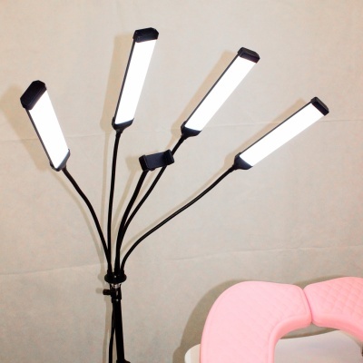 Lâmpada de pé com cinco braços luz LED branca ao lado de cadeira com almofadas rosa