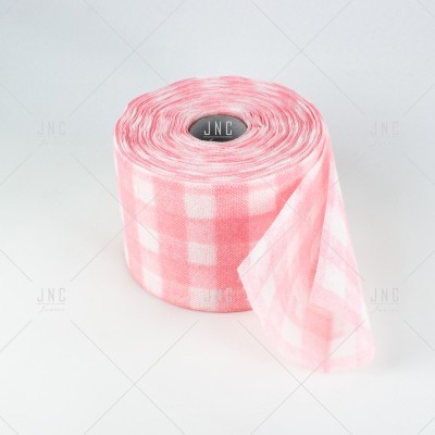 Rolo de tecido xadrez rosa e branco sobre superfície branca