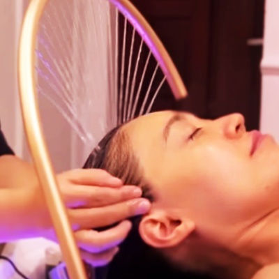 Dispositivo metálico com fios finos suspensos sobre cabeça de mulher com olhos fechados