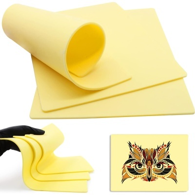 Tapetes de silicone amarelos com textura lisa, mãos com luva a segurá-los e desenho gráfico colorido de rosto de gato.