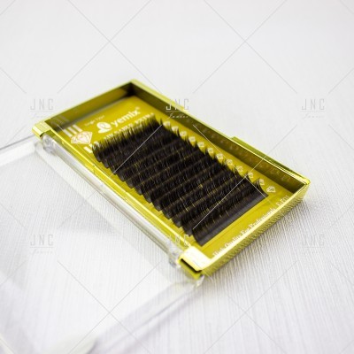 Caixa transparente com base dourada contendo pestanas negras organizadas em filas.