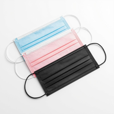 Máscaras descartáveis azul, rosa e preta sobre fundo branco