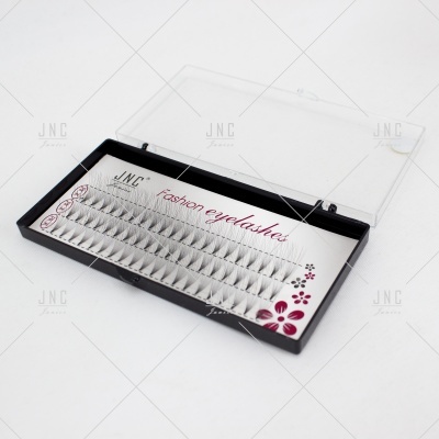 Estojo com pestanas postiços em tufos cinza claro com tampa transparente.