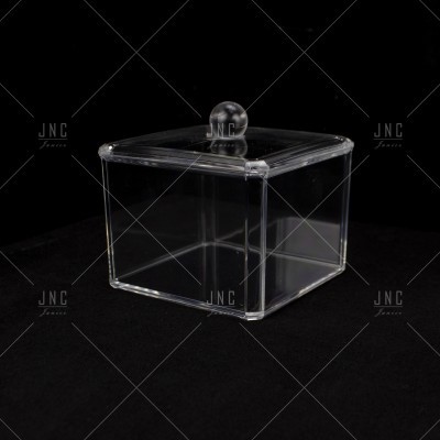 Caixa quadrada transparente com tampa e pega esférica sobre fundo preto