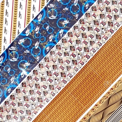 Tiras de tecido ou papel decorativo com padrões e logótipos de marcas conhecidas como NIKE, Fendi e Gucci
