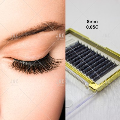 Pestanas postiças pretas de 8mm num estojo transparente ao lado de um olho com pestanas longas e curvadas