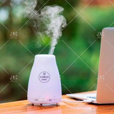 Difusor de aroma branco junto a portátil sobre mesa de madeira ao ar livre