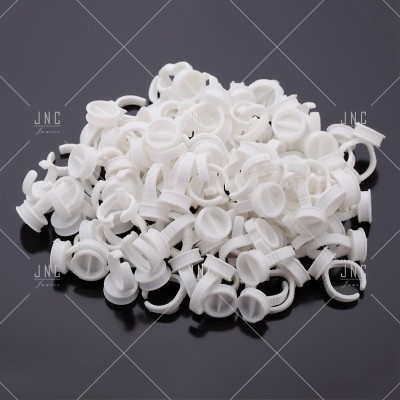 Pequenos anéis e copos de plástico branco sobre superfície preta