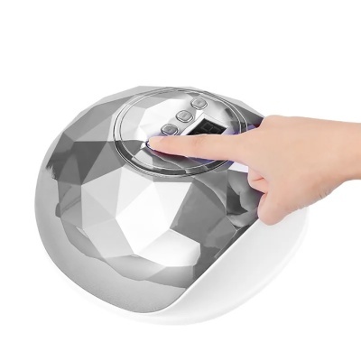 Aparelho eletrônico com superfície facetada prateada e base branca com botões e ecrã digital