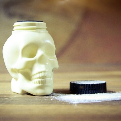 Saleiro em formato de caveira branca com tampa preta e tempero branco em pó