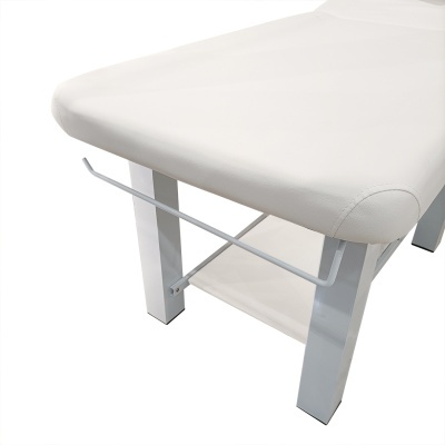 Mesa de massagem branca estofada com estrutura metálica e apoio lateral.