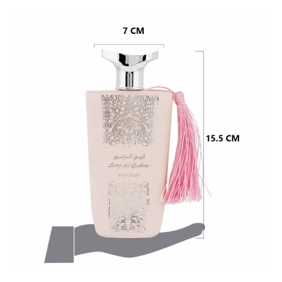 Frasco de perfume rosa claro com tampa prateada e tassel rosa pendurado