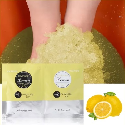 Pés dentro de gel amarelo em balde laranja com embalagem amarela de Jelly Packet Lemon e limas amarelas ao lado.