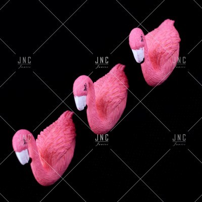 Três flamingos decorativos rosa com bicos bicolores num fundo preto
