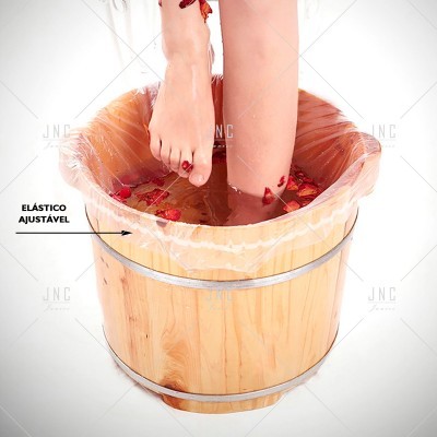 Balde de madeira com plástico interior e pés femininos a mergulhar em água com pétalas vermelhas