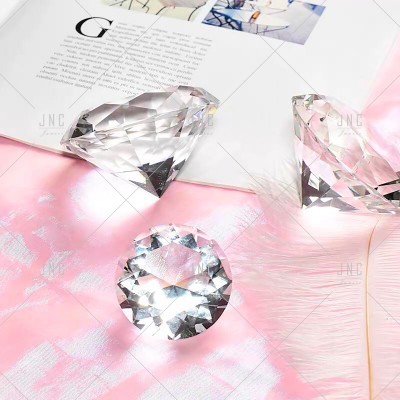 Objetos em forma de diamante transparentes em vidro sobre superfície rosa e revista aberta