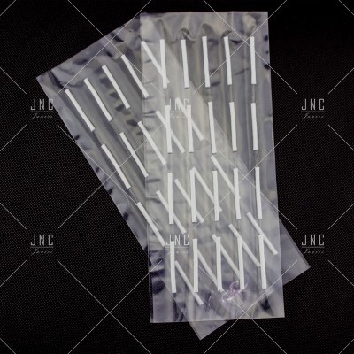 duas embalagens transparentes com palhetas brancas alinhadas verticalmente sobre fundo preto