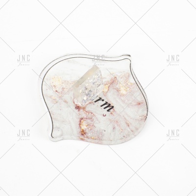 Objeto de acrílico transparente com padrão abstrato dourado e texto 'rm'