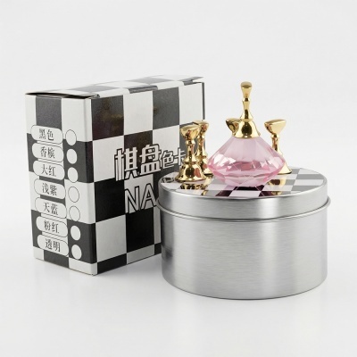 Caixa quadriculada em preto e branco e caixa metálica redonda com tampa decorada com peças douradas e objeto rosa