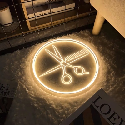 Neon redondo iluminado com tesoura e pente sobre tapete branco, perto de estante e revista.
