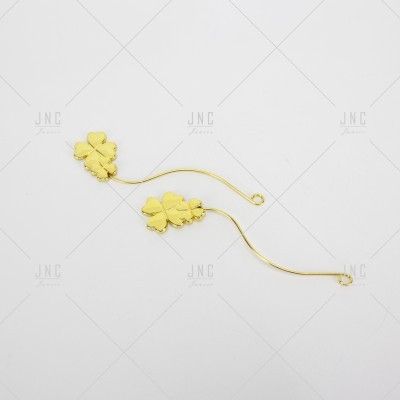 Par de brincos dourados com pendente de folha de quatro folhas sobre fundo branco