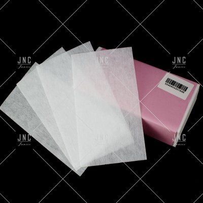 Quatro lenços de papel brancos junto a uma caixa rosa clara com etiqueta