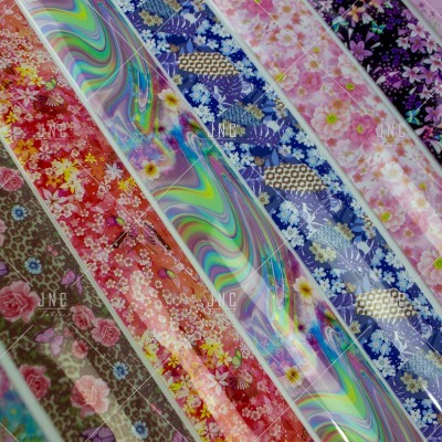 Rolos de tecido com padrões florais e psicadélicos em diversas cores, com etiquetas JNE.
