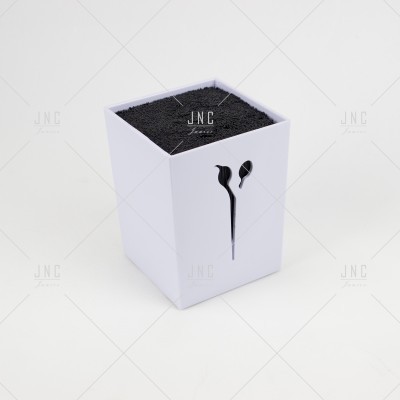 Caixa branca quadrada com recorte em forma de fones de ouvido e preenchimento preto no topo