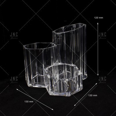 Três vasos transparentes em acrílico com formas poligonais sobre fundo preto.