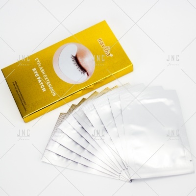 Caixa amarela com texto e várias embalagens prateadas de patch para extensão de pestanas