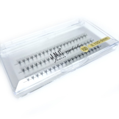 Caixa transparente com pestanas artificiais agrupadas em tufos pretos e texto visível