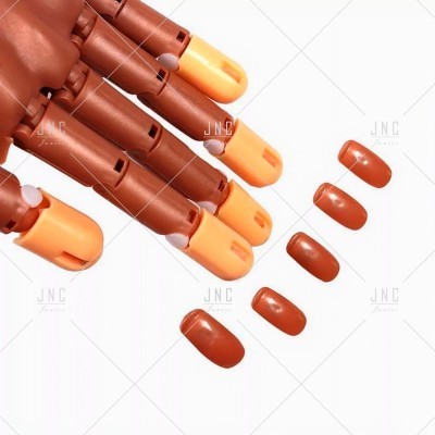 Mão de manequim em plástico castanho com unhas artificiais castanhas