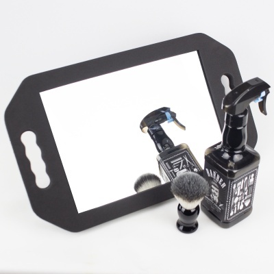 Espelho de apoio com pega preta, spray preto com rótulo branco e pincel de barbear preto com cerdas cinzentas