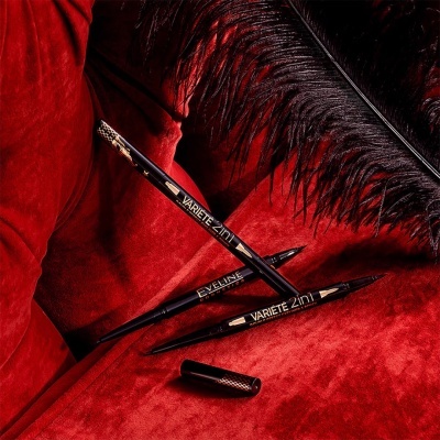 Três lápis de maquilhagem pretos Variete 2in1 e Eyeliner sobre veludo vermelho com pena preta ao lado