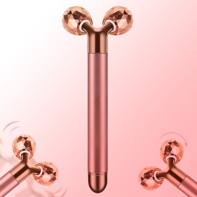 Dispositivo de massagem manual metálico rosado com esferas facetadas cobre em fundo rosa