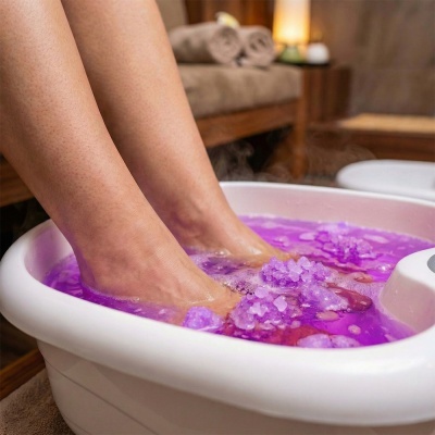 Banho de pés com cristais aromáticos roxos em bacia branca