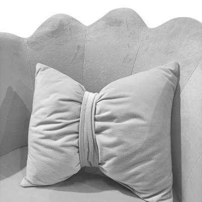 Almofada cinzenta em forma de laço num sofá cinzento claro