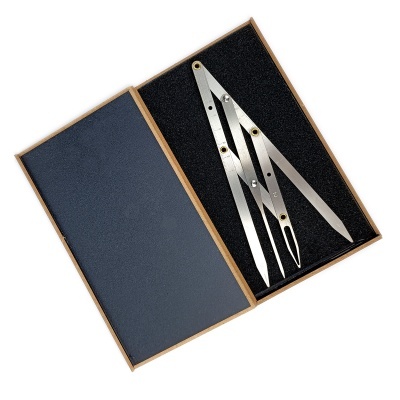 Conjunto de instrumentos de desenho técnico metálicos numa caixa aberta.