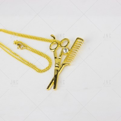 Colar dourado com pendente de tesoura e pente
