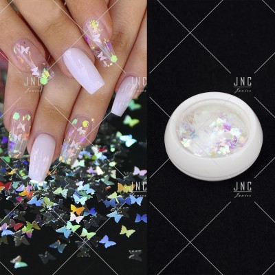 Unhas decoradas com glitter em forma de borboletas e frasco branco com glitter
