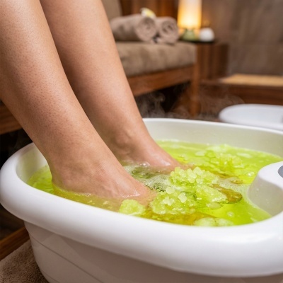 Pés em bacia branca com água verde e sal grosso, fundo de spa