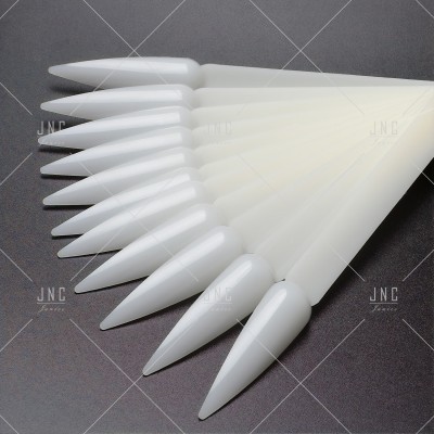 Unhas postiças brancas pontiagudas em leque sobre fundo escuro